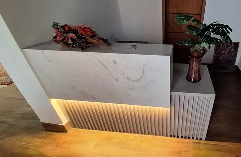Balcão de recepção revestido em pedra clara, com luz embaixo