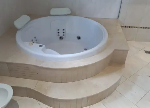 Banheira de hidromassagem com degrau e revestimento em mármore bege