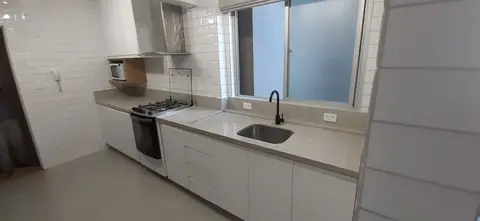 Cozinha com bancada de pedra cinza clara e cuba embutida sob a janela