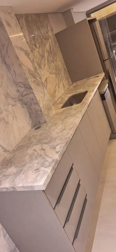 Bancada de cozinha e coluna revestidas com pedra de veios cinza