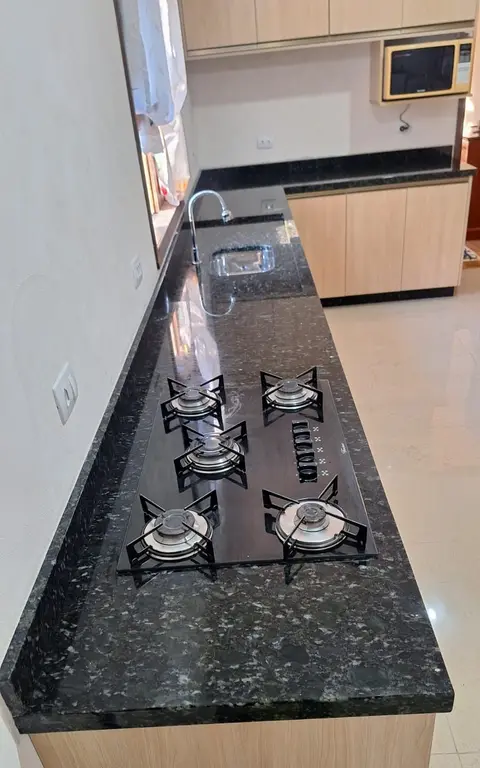 Bancada de granito escuro com cooktop de cinco bocas embutido