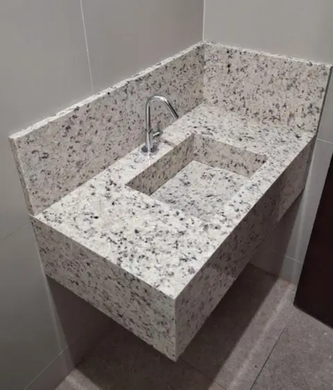 Cuba esculpida em granito claro, com frontão e saia