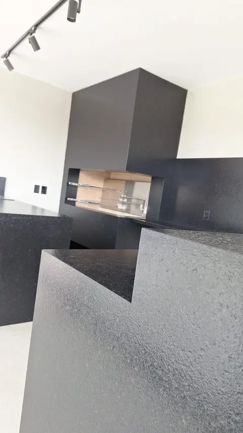 Quina de bancada em granito preto com acabamento texturizado, perto da churrasqueira