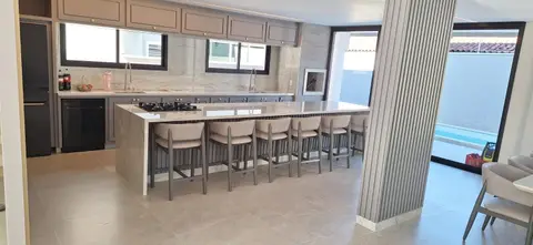 Ilha de cozinha em pedra clara com a lateral até o chão e oito banquetas