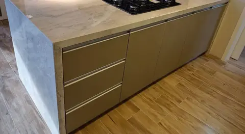 Ilha com cooktop em pedra de veios cinza, com a lateral emendada em meia-esquadria