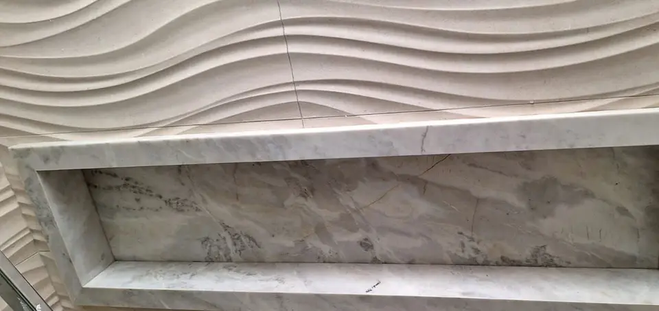 Nicho em mármore embutido em parede de textura ondulada