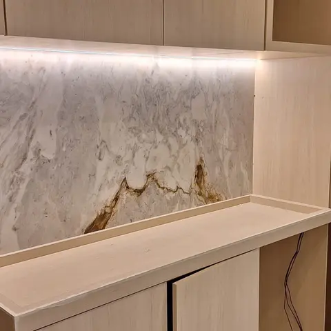 Painel de pedra clara com veio dourado sobre aparador
