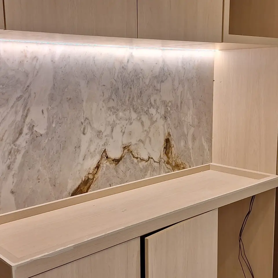 Painel de pedra clara com veio dourado sobre aparador